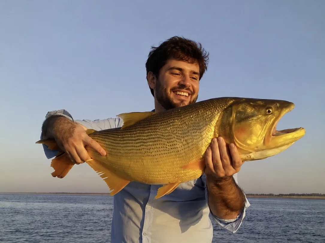 Pescador sosteniendo un gran dorado durante una salida en el río Paraná